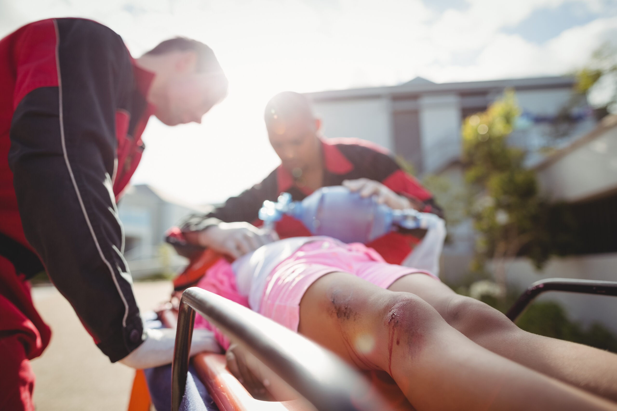 Paramedic giving oxygen to injured girl at accident spot